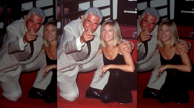 James Brolin crouched down and pointing to the camera with his arm around wife Barbra Streisand at his Hollywood Walk of Fame ceremony.