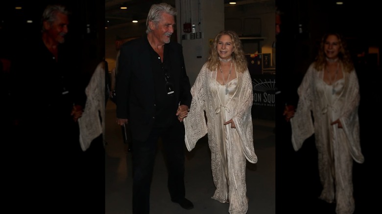 James Brolin in an all-black suit holding hands with Barbra Streisand wearing a sparkly silver outfit.