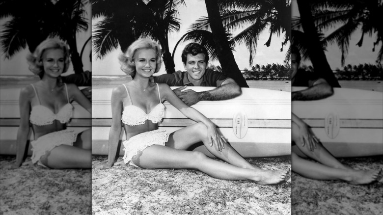 Shelley Fabares in a white bikini and Fabian posing next to a surfboard in a promotional photo for "Ride the Wild Surf" in 1964.