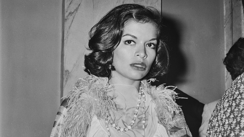 Bianca Jagger pictured in the 1970s wearing a feathered jacket and dress.