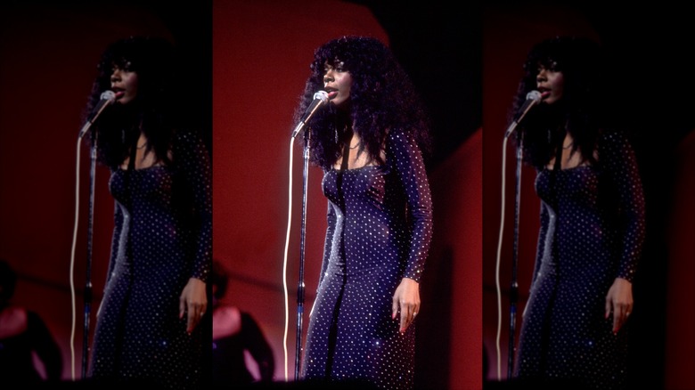 Donna Summer sings into a microphone while on stage