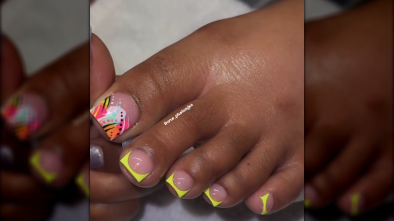 A pedicure with neon French tips and a multicolored '90s design