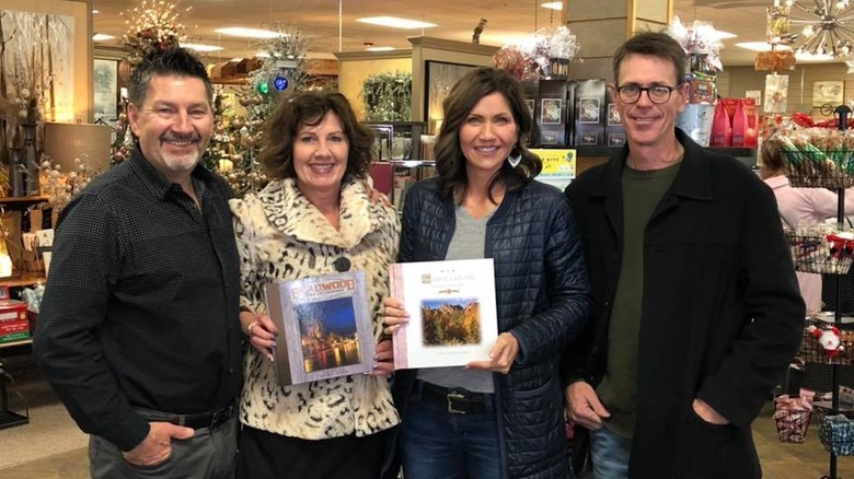Kristi Noem holding a book in a store while wearing little makeup