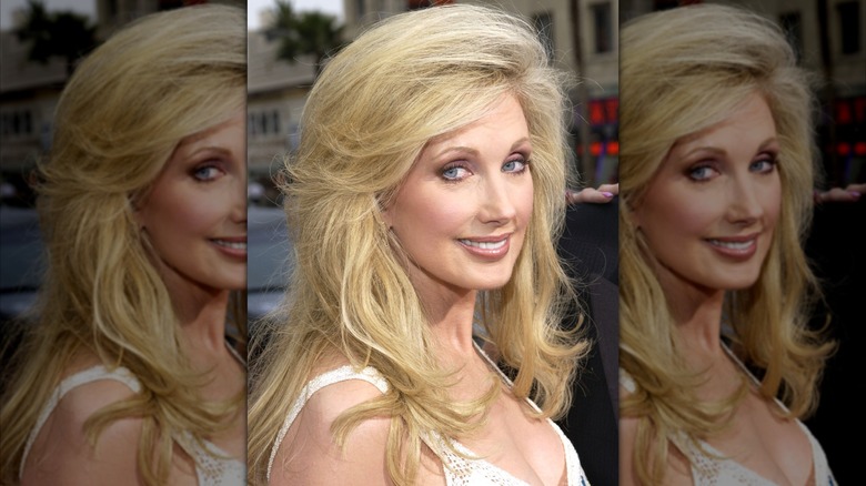 Morgan Fairchild in 2023 with lightly feathered hair wearing a white dress.