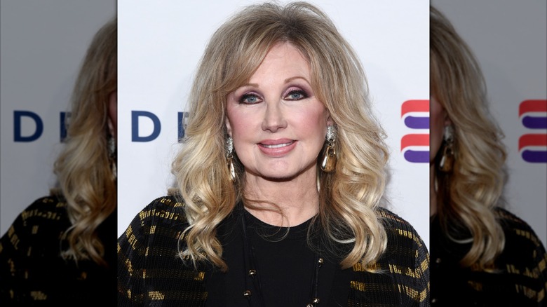 Morgan Fairchild wearing black at an event in 2019 with softly curled hair.