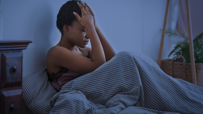 Stressed woman sitting up in bed