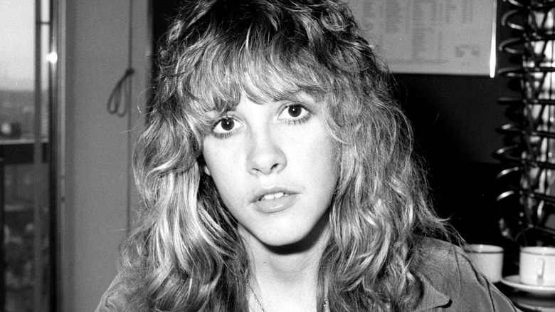 Black and white photo of Stevie Nicks with long, shaggy hair and bangs in 1977.