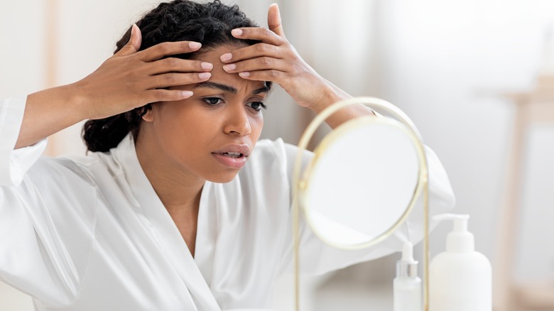 Woman inspecting her skin in the mirror