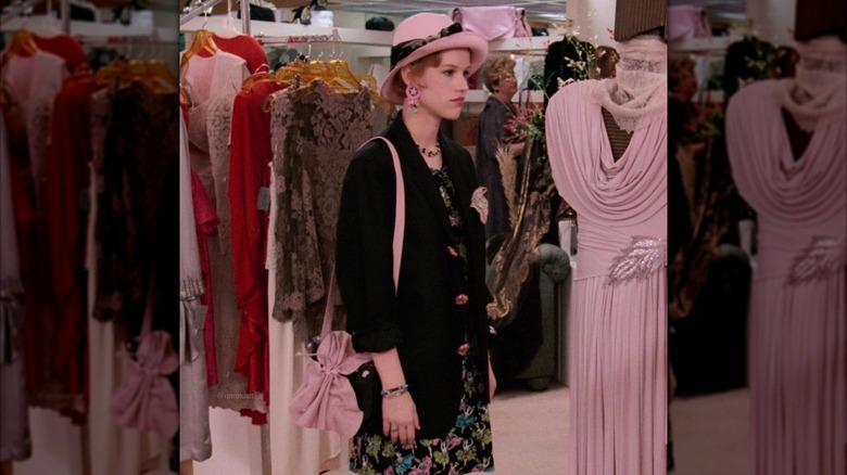 Molly Ringwald pictured as Andie Walsh wearing a black blazer, floral dress, and pink hat in Pretty in Pink