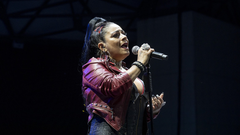 Lisa Velez performing on stage wearing a red leather jacket with a high ponytail.