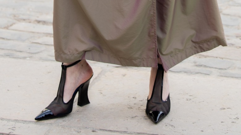 Woman wearing a brown coat with black T-strap heels.