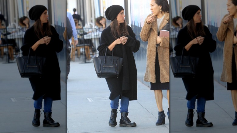 Soleil Moon Frye on the street wearing jeans, a black coat, a black beanie, and black combat boots with a large black purse.
