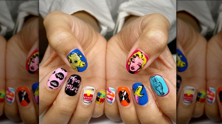 Close up image of an Andy Warhol inspired manicure featuring various graphic designs.