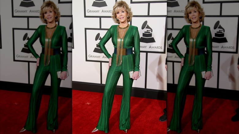 Jane Fonda posing on the Grammy's red carpet wearing an emerald-green jumpsuit with gold embellishments.