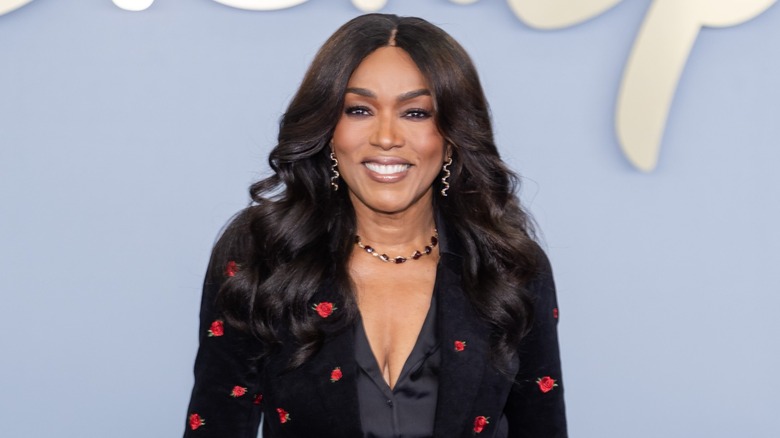 Angela Bassett wore her black hair in relaxed waves and a middle part along with long earrings and a black jacket with a red floral print and a low-cut black blouse underneath while attending the 2026 Disney Upfront in New York City.