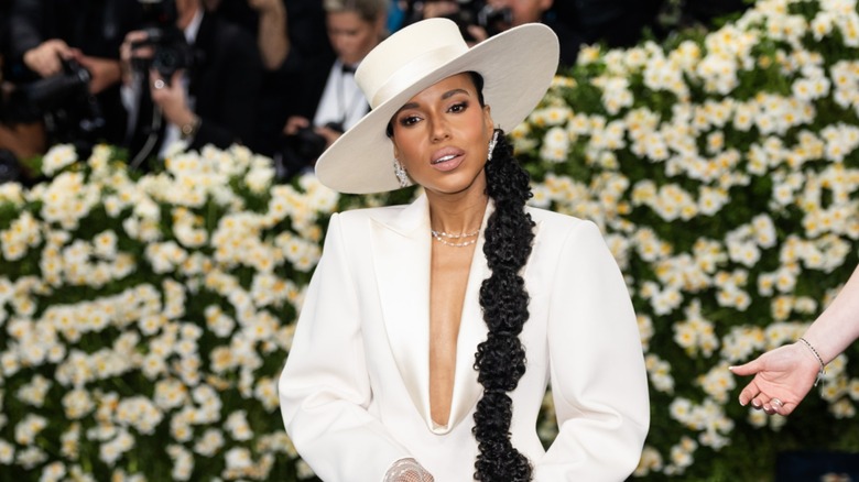 Kerry Washington wearing a white wide-brimmed hat and white top with a plunging neckline at the Met Gala in 2025.