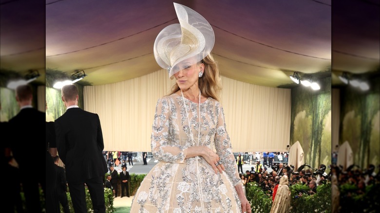 Sarah Jessica Parker posing at the 2024 Met Gala  wearing a peach dress and ornate hat.