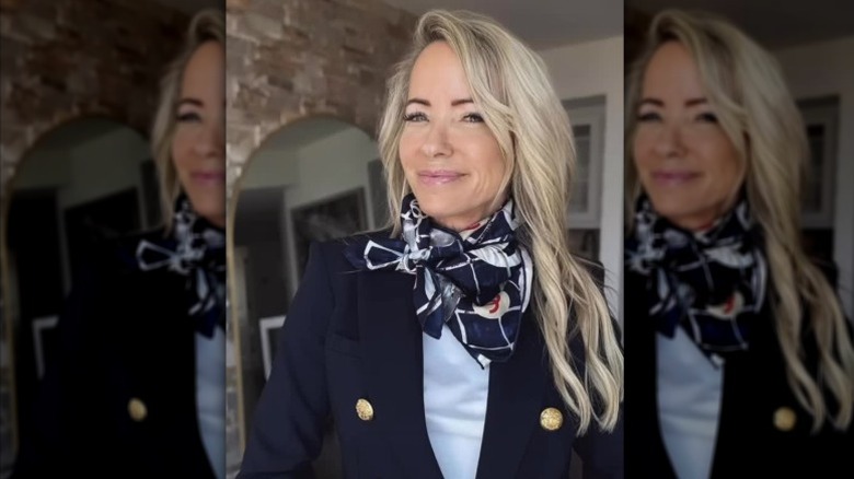 A woman with long hair with face-framing pieces wearing a blazer and scarf.