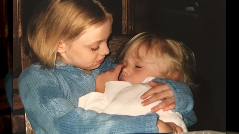 Young Dakota Fanning holds a sleeping toddler Elle Fanning in her arms