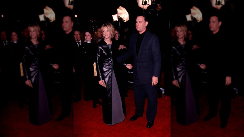 Meg Ryan wearing a floor-length leather jacket standing next to Tom Hanks on the red carpet.