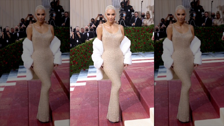 Kim Kardashian poses wearing a nude gown and a white fur coat