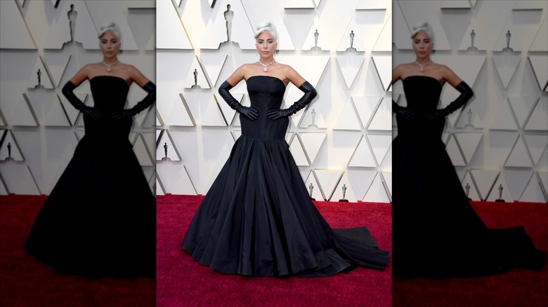 Lady Gaga poses with her hands on her hips wearing black gloves