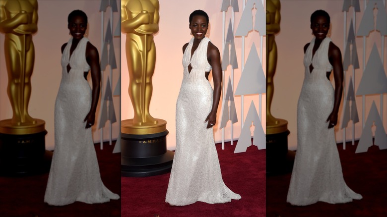 Lupita Nyong'o smiles wearing a white pearl gown