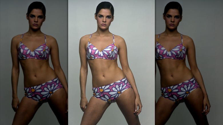 Ali MacGraw posing in a daisy-print bikini with slicked-down hair.