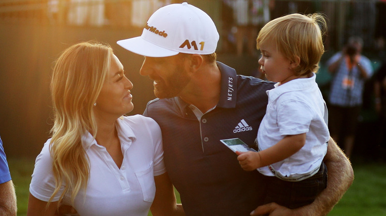 Paulina Gretzky, looking at Dustin Johnson as he holds their son, Tatum Johnson, at a golf tournament in 2016.