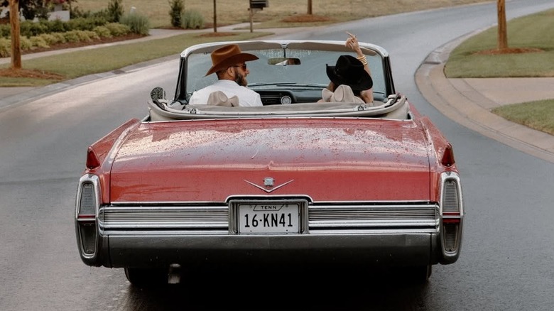 Dustin Johnson driving Paulina Johnson and their sons, Tatum and River Johnson, in a convertible.