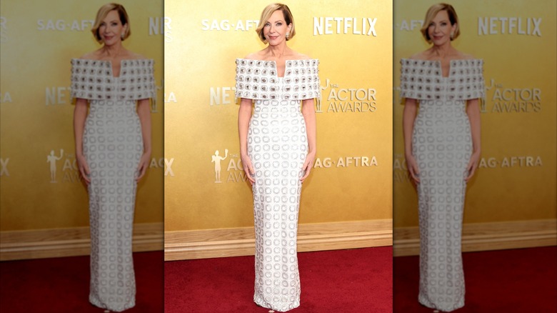 Allison Janney posing on the red carpet in a geometric-print, off-the-shoulder white dress.