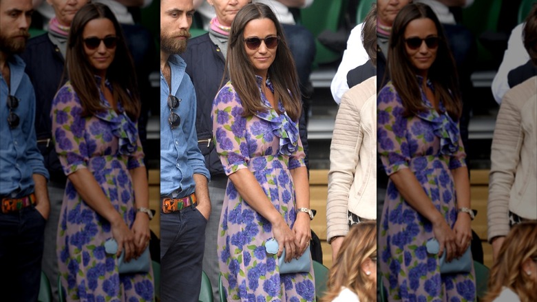 Pippa Middleton wearing a purple floral dress with sunglasses holding a blue clutch at Wimbledon in 2016.