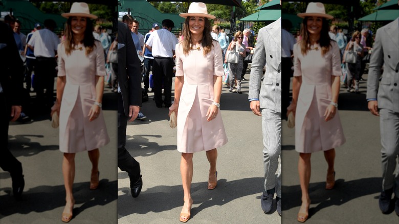 Pippa Middleton wearing a light pink dress and fedora hat walking at Wimbledon in 2019.