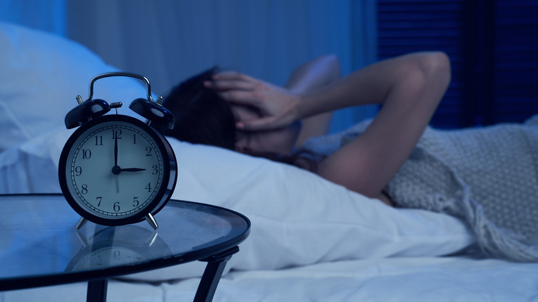 Woman awake in bed next to clock