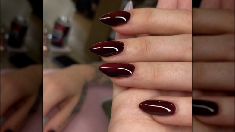 A claw manicure with dark burgundy nail polish