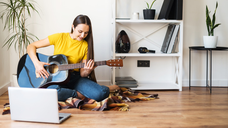 Woman playing guitar with laptop