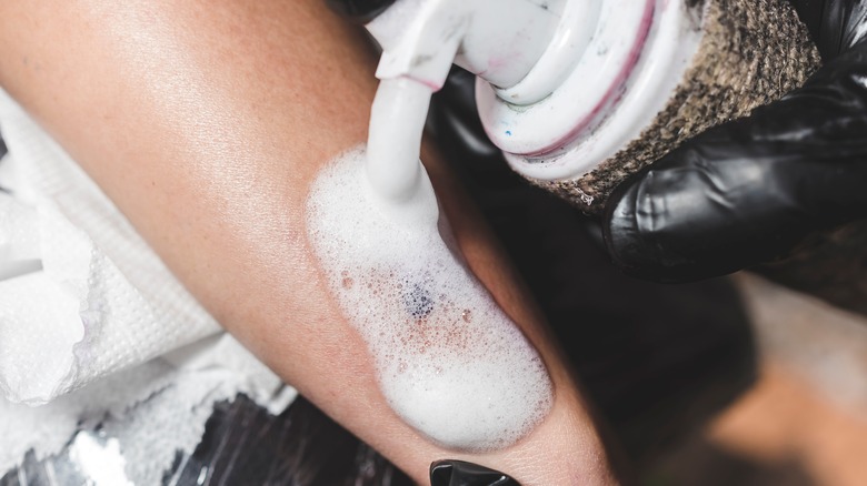 Tattoo artist applying soap to fresh tattoo