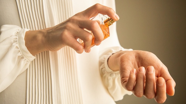 Woman spraying perfume on wrist