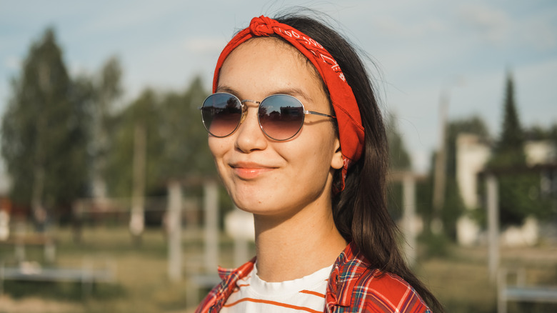 A woman accessorizing with sunglasses and a bandana