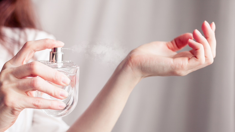 Woman spraying herself with perfume