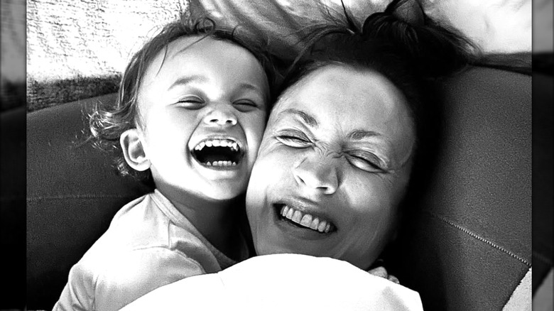Kaley Cuoco and daughter Matilda laugh together while cuddled up in a black-and-white photo.