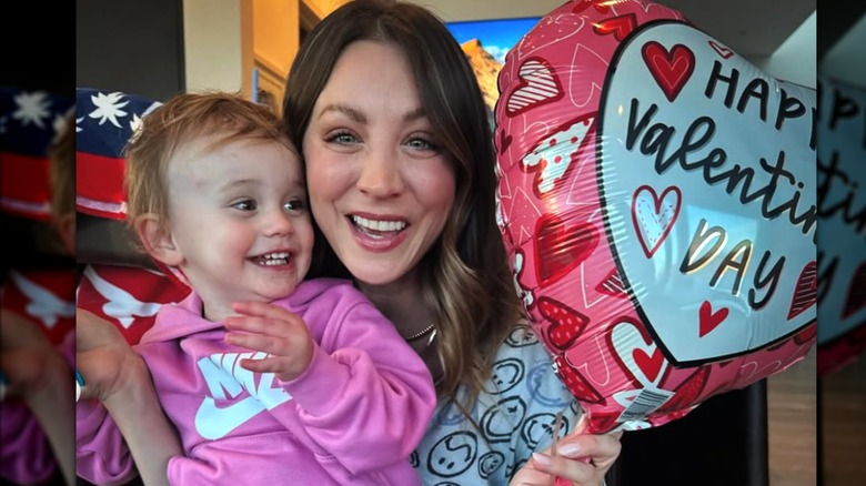 Kaley Cuoco's daughter Matilda sits on her lap while the duo smiles and poses with a Valentine's Day balloon.
