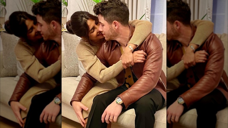 Priyanka Chopra and Nick Jonas hold each other while sitting together on a couch