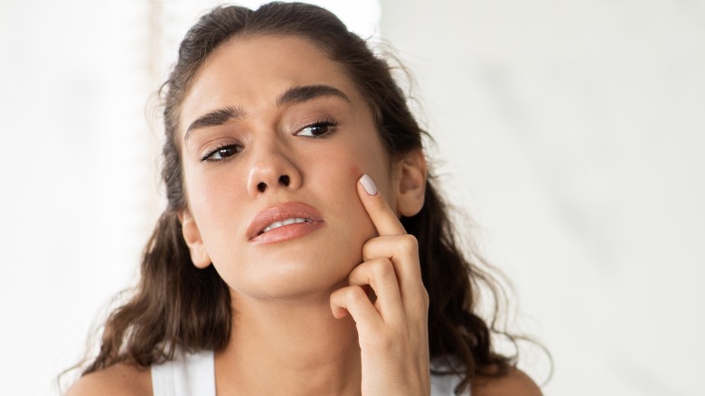 Woman looking at a pimple in a mirror