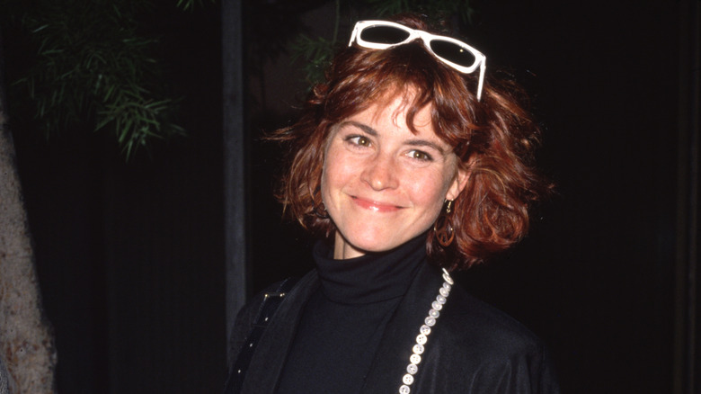 Ally Sheedy in 1989 wearing a black outfit and white sunglasses perched on her head.