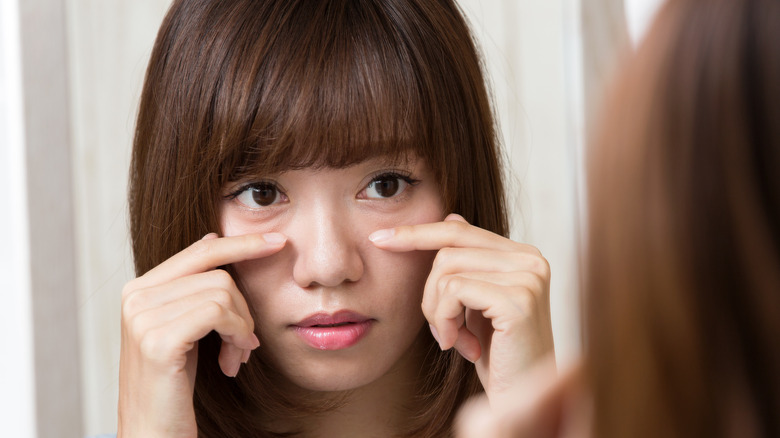 Woman examining puffy eye bags