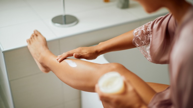 woman rubbing lotion on legs