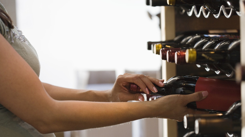 Woman grabbing wine bottle