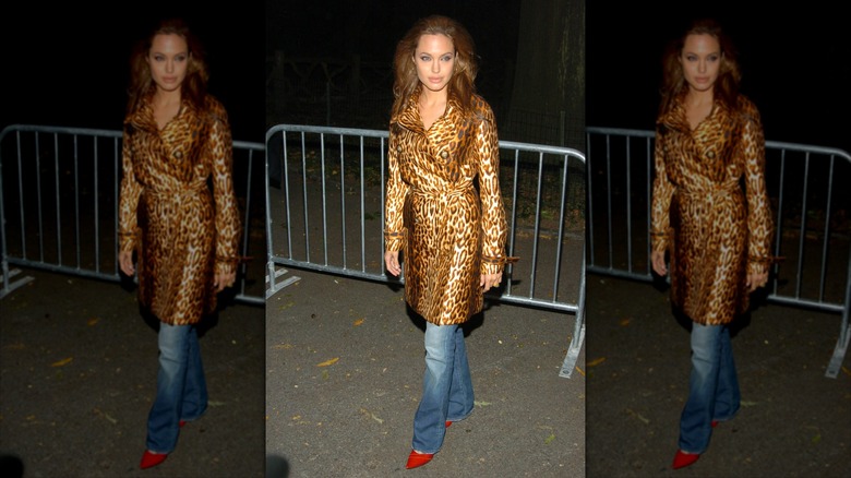 Angelina Jolie poses wearing flared jeans and a leopard print coat.