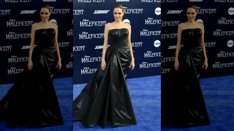 Angelina Jolie smiles wearing a leather strapless gown.